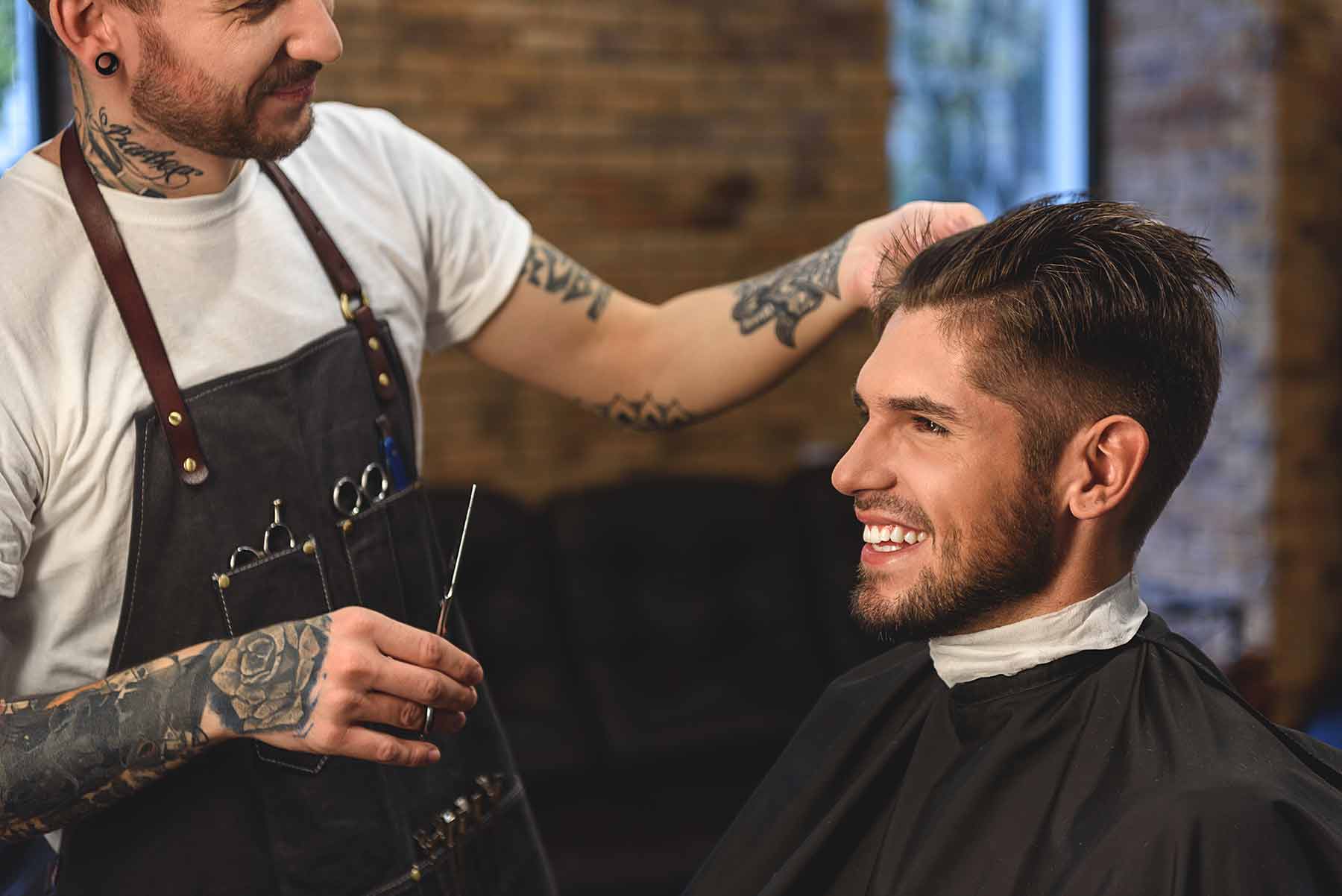 A male client receiving a stylish haircut in a modern barber shop