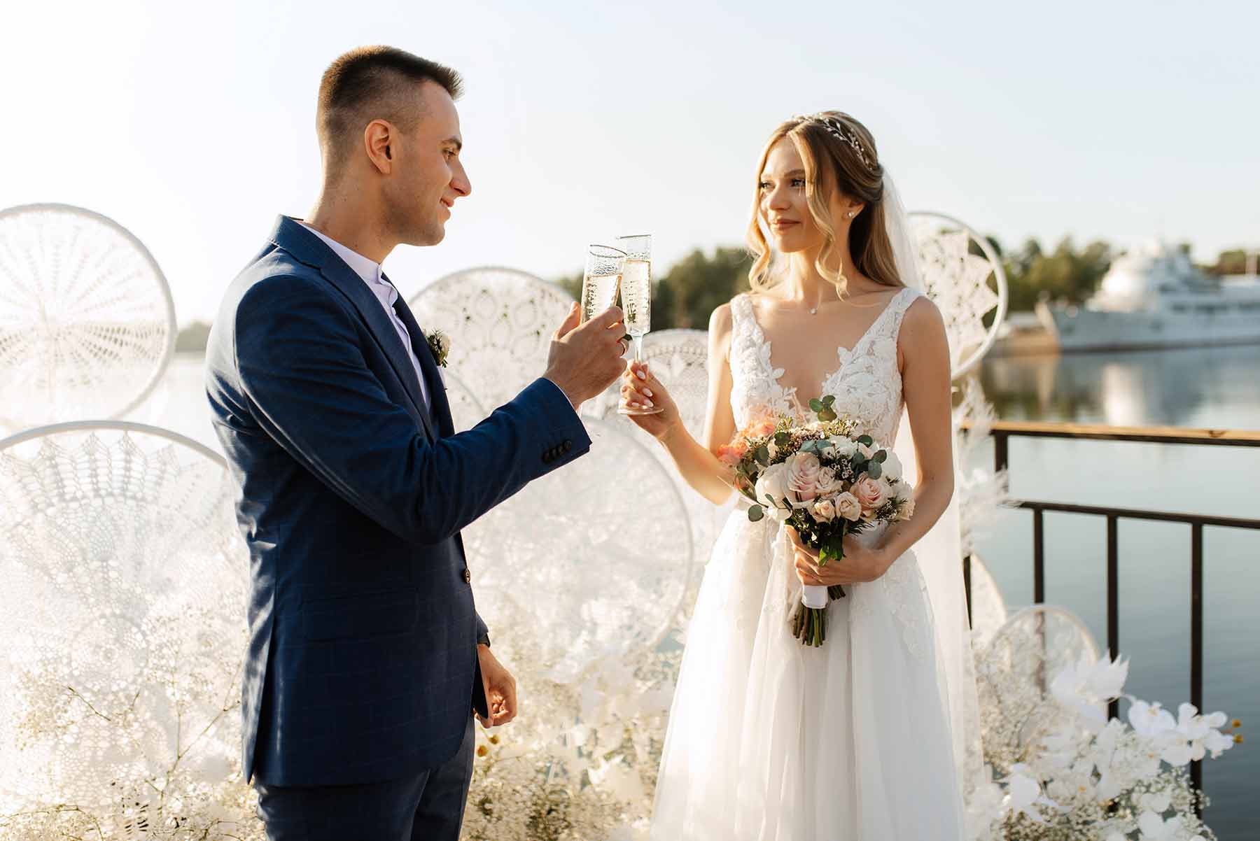 A newlywed couple toasting with champagne on the deck of a cruise ship