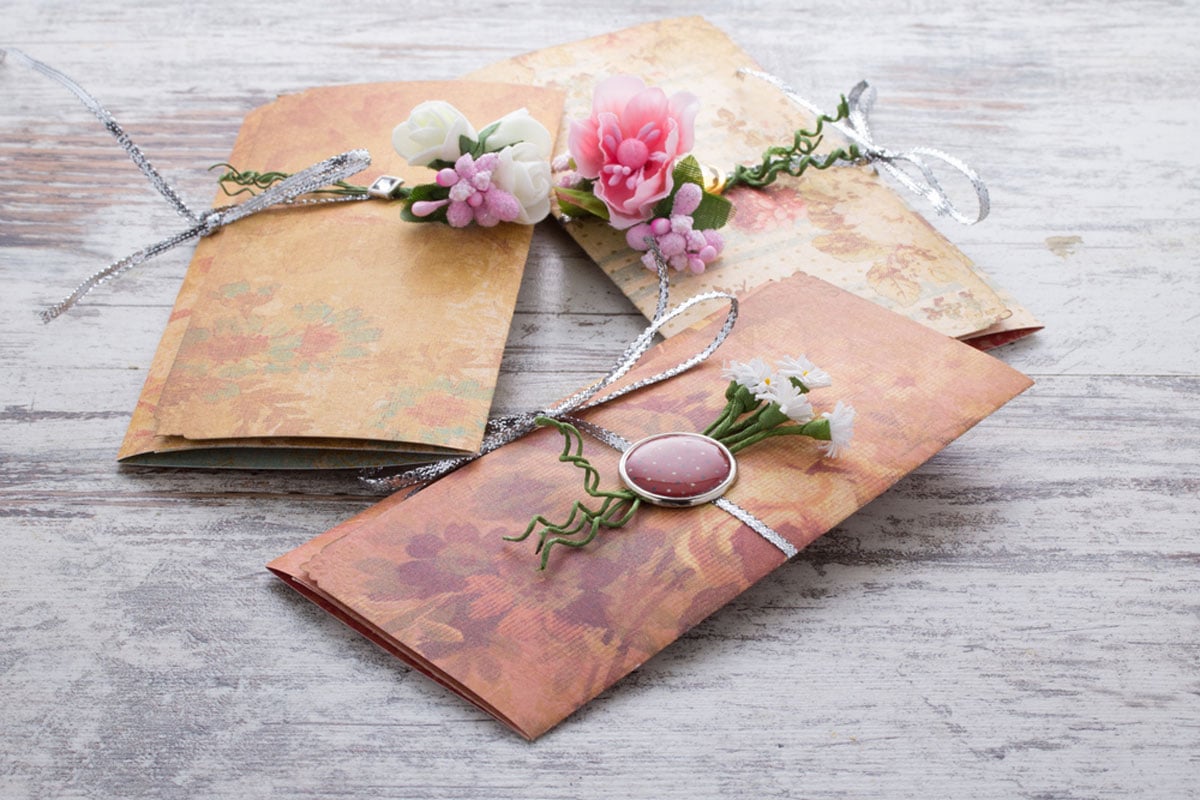 Handmade wedding invitations made of vintage paper with buttons ribbons and flower add ons