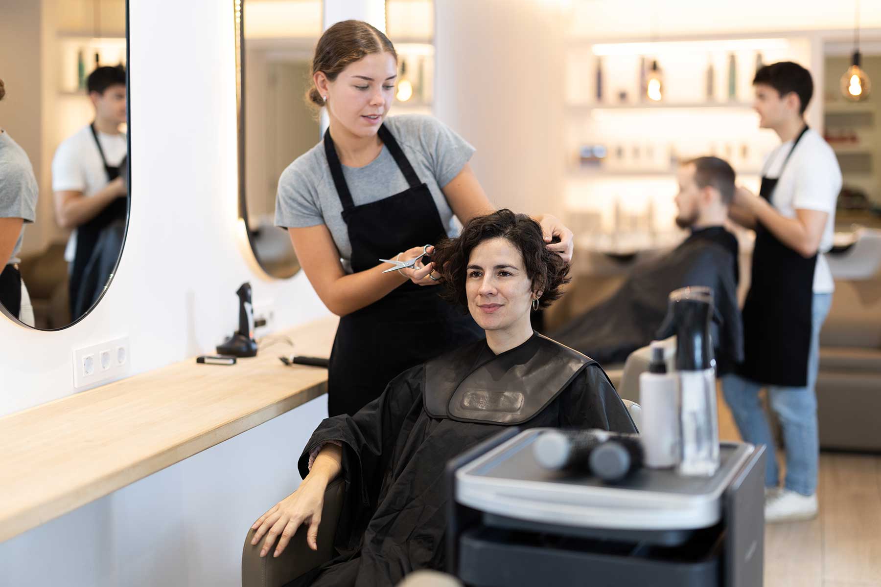 Young hairdresser giving a haircut to a client in a beauty salon