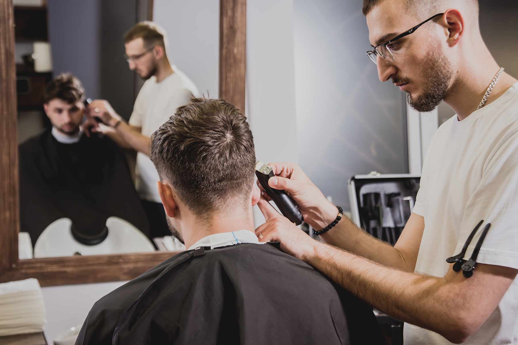 A barber trimming a client’s hair using an electric razor inside the barbershop
