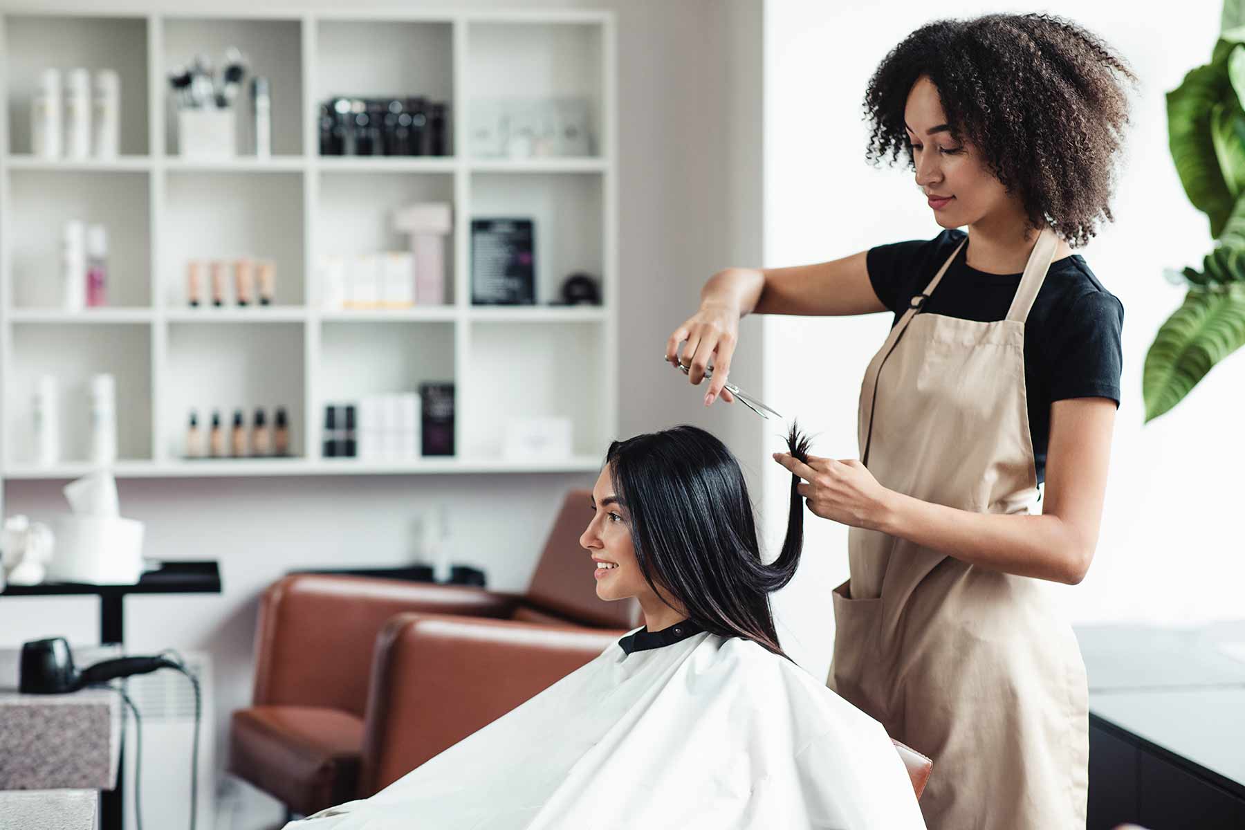 A happy client getting a haircut from a hairstylist in a modern salon