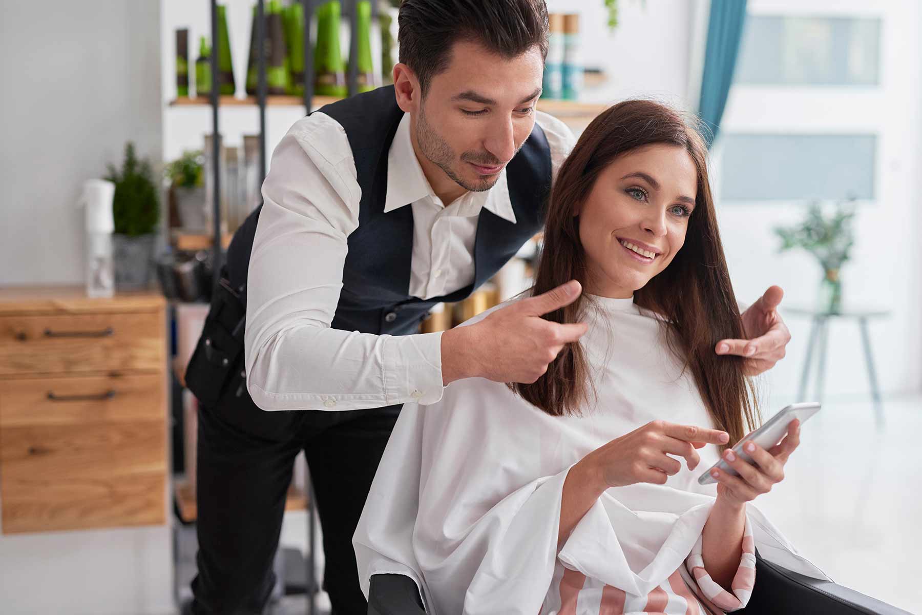 A male hairstylist asking a client on her preferred haircut