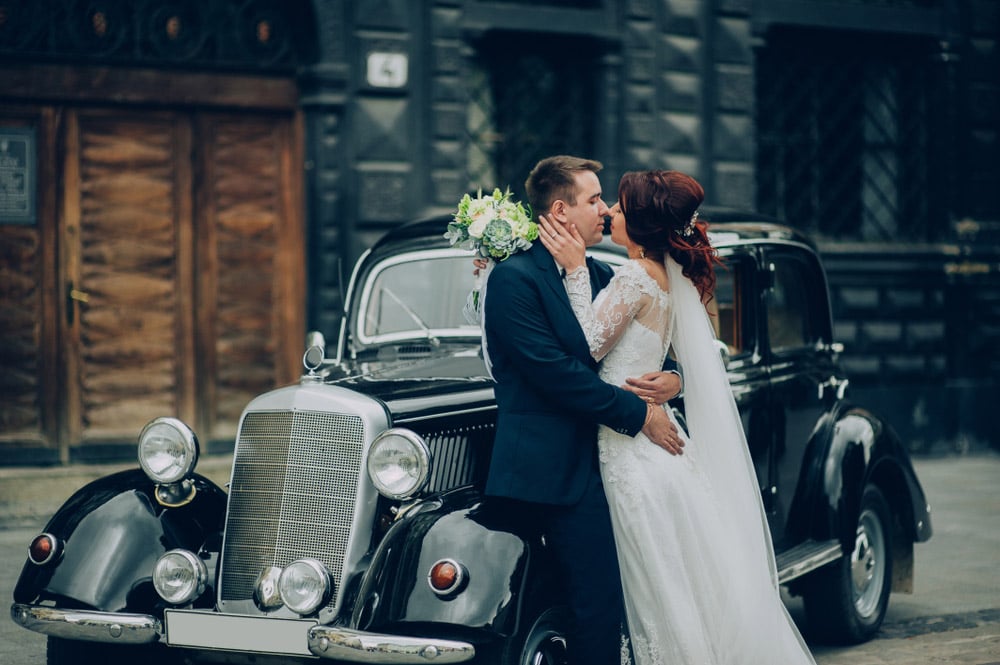 Couple posing in front of antique car